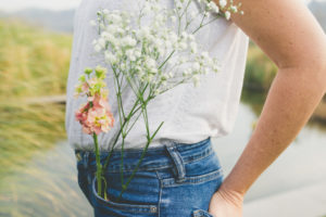 mujer de costado se ve solo su cintura con un ramo de flores en el bolsillo